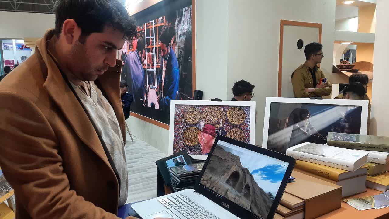 مردی در حال مشاهده تور مجازی طاق‌بستان روی صفحه لپ‌تاپ در نمایشگاه گردشگری مجازی